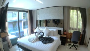A hotel room with a large bed, a desk, a chair, and a view of the outside. - B507 - 1 Bedroom Condo Top Floor Pool View, Ao Nang (Krabi)
