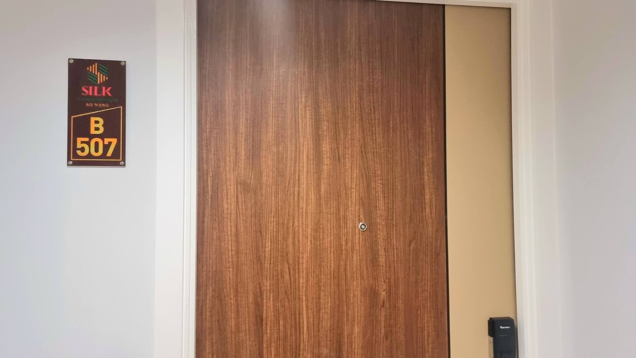 Eine Holztür mit einem Schild darüber, auf dem "SILK AO NANG B 507" steht.