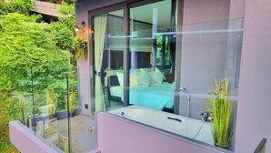 A modern bedroom with a glass wall, a large window, and a bathtub. - B507 - 1 Bedroom Condo Top Floor Pool View, Ao Nang (Krabi)