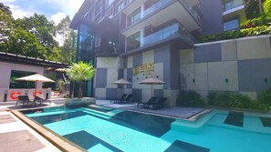 A modern building with a swimming pool, lounge chairs, and umbrellas. - B507 - 1 Bedroom Condo Top Floor Pool View, Ao Nang (Krabi)