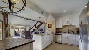 A spacious kitchen with white cabinets, a stainless steel refrigerator, and a wooden island. - Stunning 4 Bedroom Mountain Cabin with Hot Tub and Game Room, near Theme Parks (Sevierville)