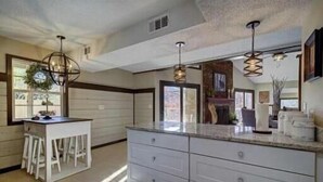 A kitchen with a white countertop, a bar stool, and pendant lighting. - Stunning 4 Bedroom Mountain Cabin with Hot Tub and Game Room, near Theme Parks (Sevierville)