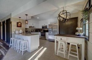 A modern kitchen with white cabinetry, stainless steel appliances, and a central island with bar stools. - Emma's Rare Find by Beyond Expectations: Remodeled Home w/ Hot Tub & Game Room (Sevierville)