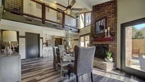 A spacious living area with a high ceiling, a fireplace, and a dining table. - Stunning 4 Bedroom Mountain Cabin with Hot Tub and Game Room, near Theme Parks (Sevierville)