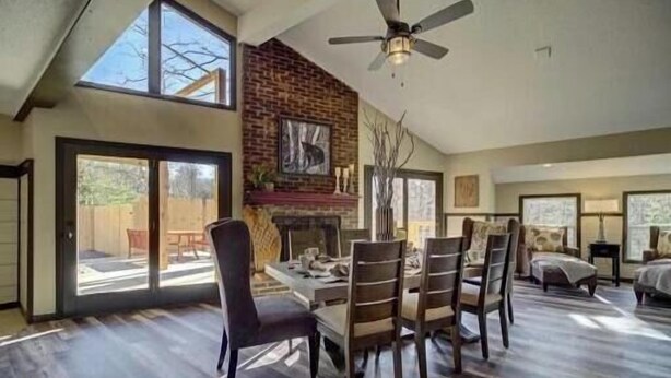A spacious living room with a fireplace, large windows, and a dining area with chairs and a table. - Stunning 4 Bedroom Mountain Cabin with Hot Tub and Game Room, near Theme Parks (Sevierville)
