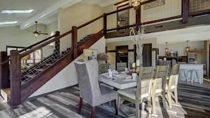 A spacious dining area with a high ceiling and a staircase leading to an upper level. - Stunning 4 Bedroom Mountain Cabin with Hot Tub and Game Room, near Theme Parks (Sevierville)