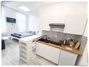 Ett litet rum med en säng, ett litet skrivbord och ett litet pentry.
