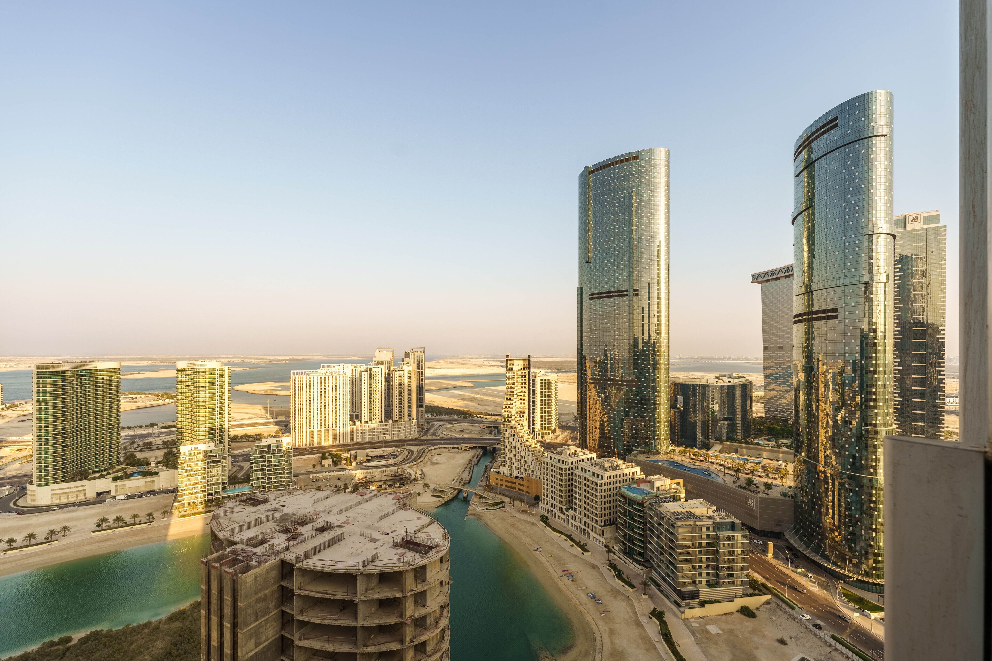 A high-rise urban area with modern skyscrapers, a marina, and a river.