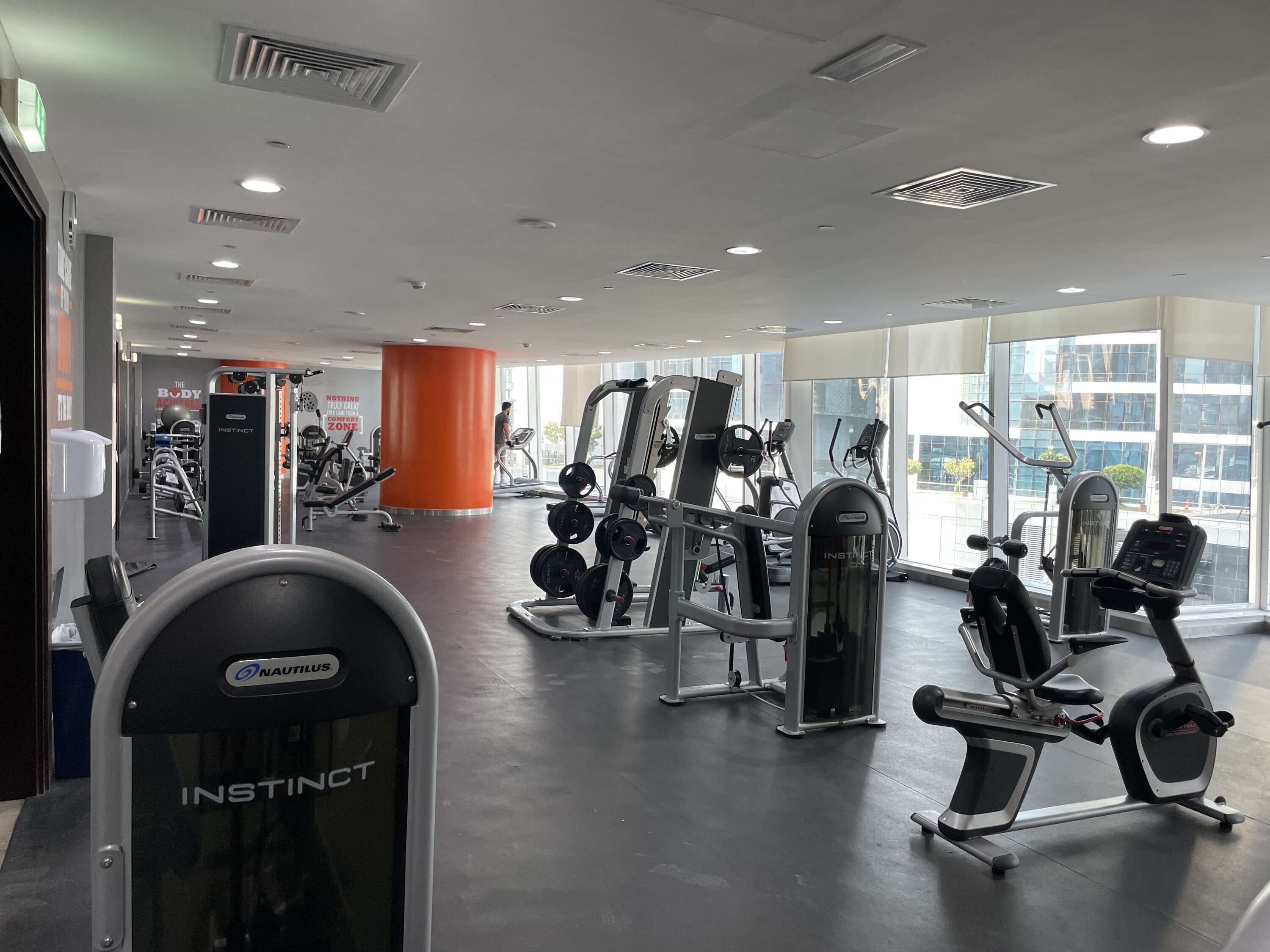 Un gimnasio con equipamiento Nautilus e Instinct, ventanas amplias y vista a la ciudad.