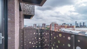 A balcony with a city view, featuring a metal railing with circular cutouts and a wooden floor. - Fabulous Studio in Central Liverpool (Liverpool)
