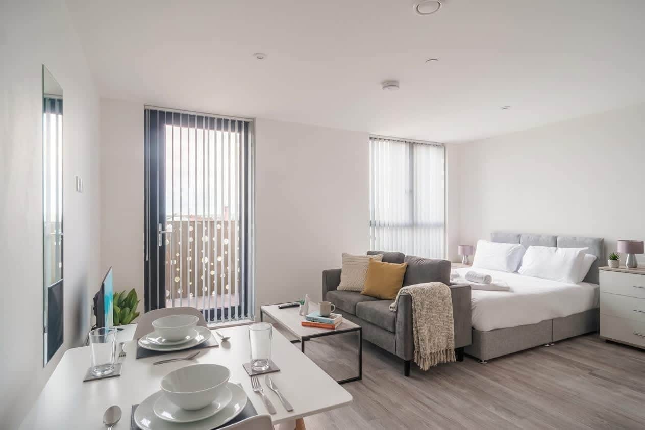 A modern, well-lit living room with a dining area, a sofa, and a bed.