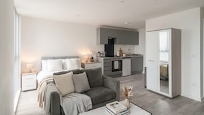 A modern apartment with a living area, a kitchenette, and a bedroom.