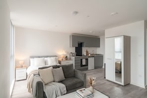 A modern apartment with a living area, a kitchenette, and a bedroom.