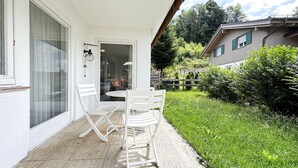 Een wit gebouw met een terras, compleet met een tafel en twee stoelen.