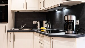 Een moderne keuken met witte kastjes, een zwart aanrecht en een ingebouwde koffiezetapparaat.