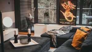A modern living room with a dark grey sofa, a small side table with candles, and a poster on the wall.