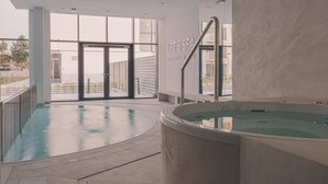 An indoor pool area with a hot tub, large windows, and a sign reading 'LET'S SEA BALTIC SEA.'