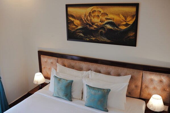 Habitación de hotel con una cama grande, dos almohadas, cabecero y un cuadro colgado en la pared.