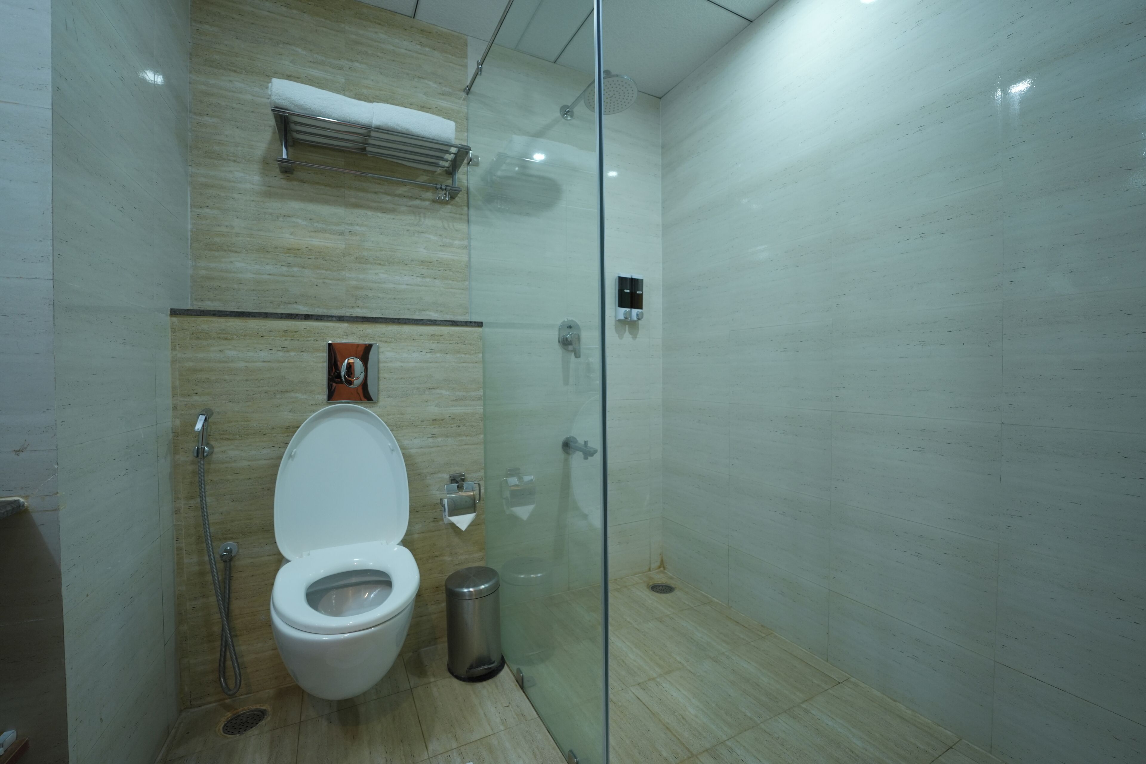 Un baño moderno con ducha envuelta en vidrio, inodoro y secamanos.
