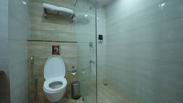 Un baño moderno con ducha envuelta en vidrio, inodoro y secamanos.