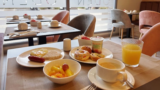A breakfast setting with plates of food, a cup of coffee, and a glass of orange juice. - Hôtel Oden Paris Ivry (Ivry-sur-Seine)