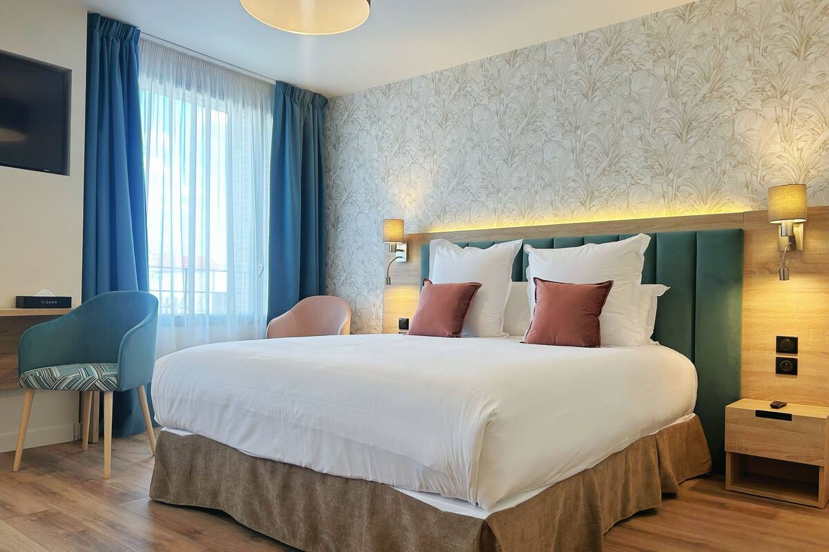 Ein Hotelzimmer mit einem großen Bett, einem Schreibtisch, einem Sessel und einem Nachttisch.