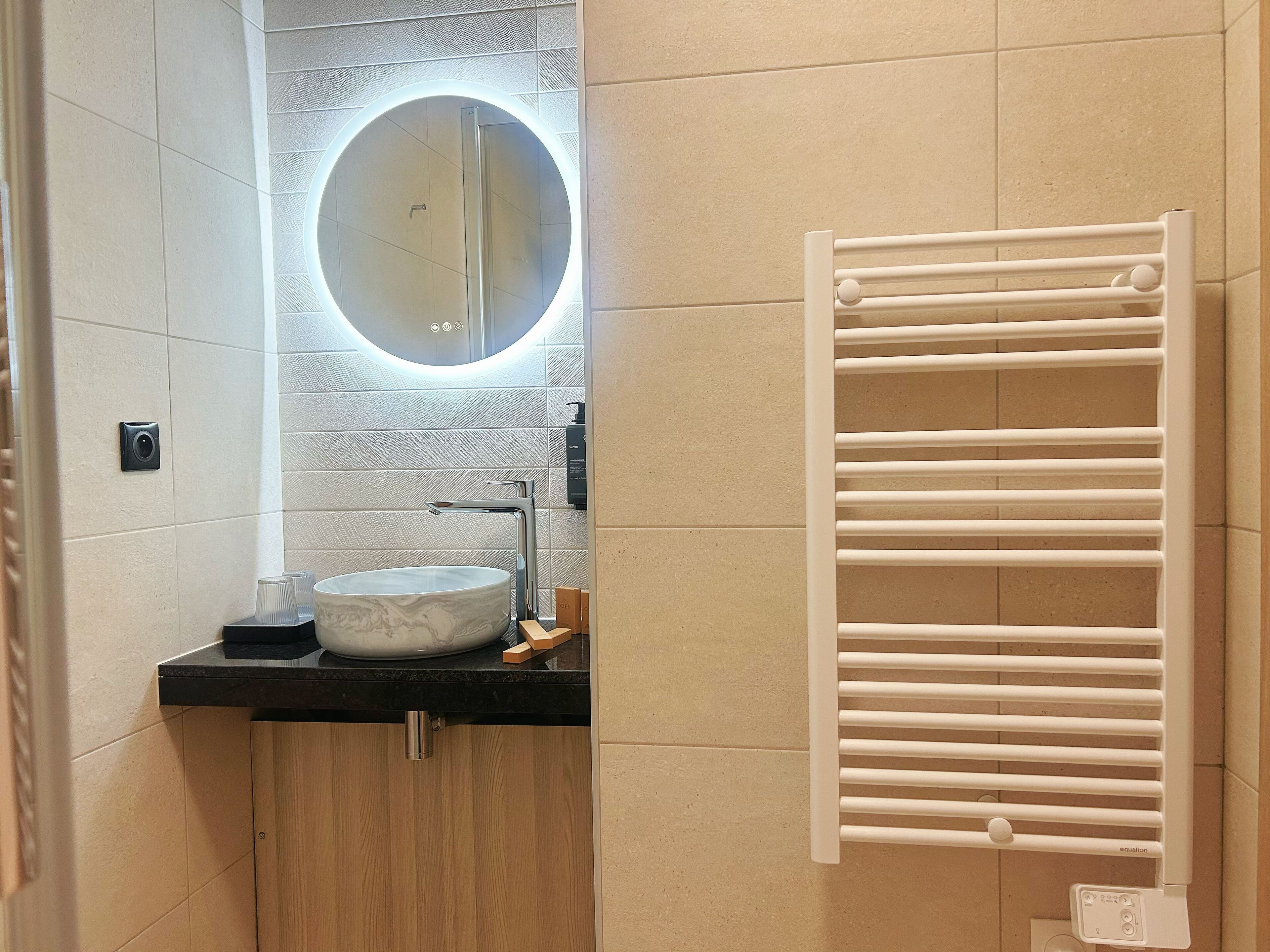 A bathroom with a round mirror, a sink, and a towel rack.