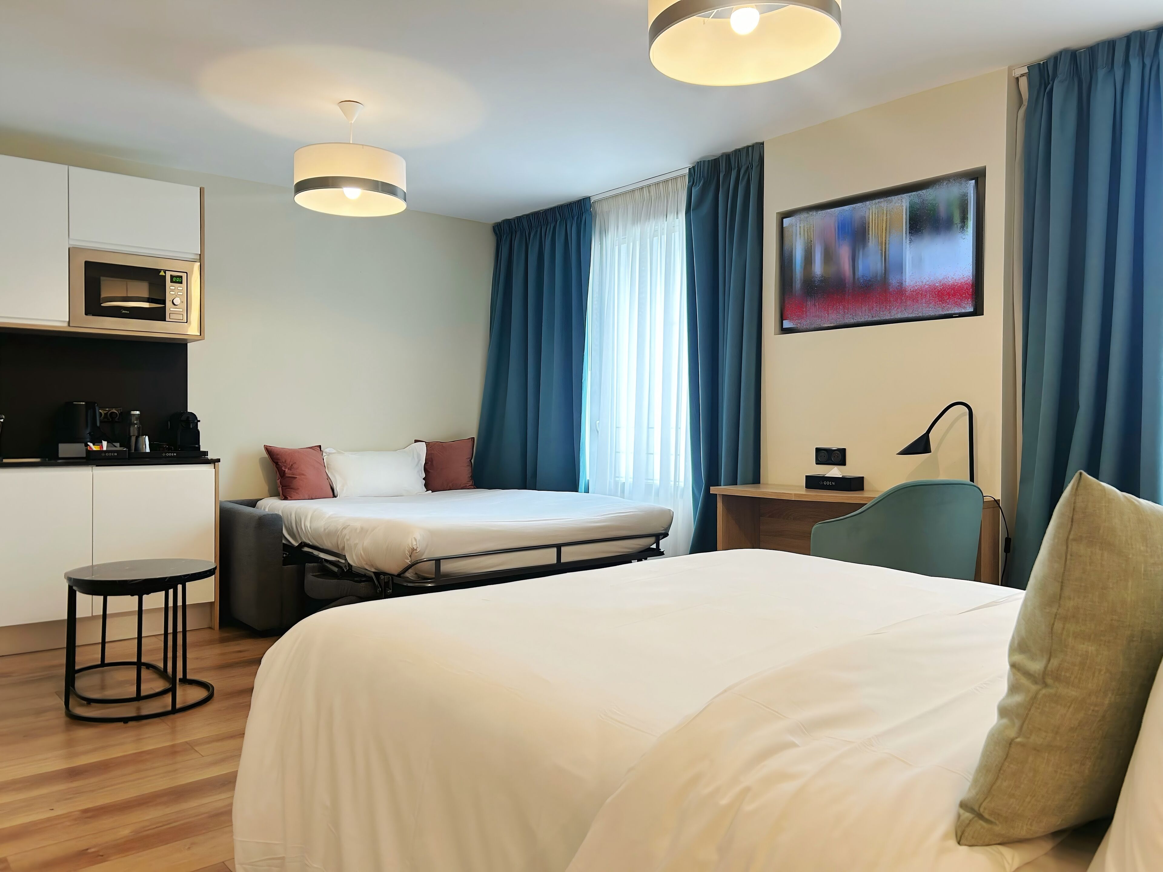 Una habitación de hotel con cama, escritorio, silla, cafetera y microondas.