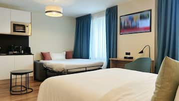 Una habitación de hotel con cama, escritorio, silla, cafetera y microondas.
