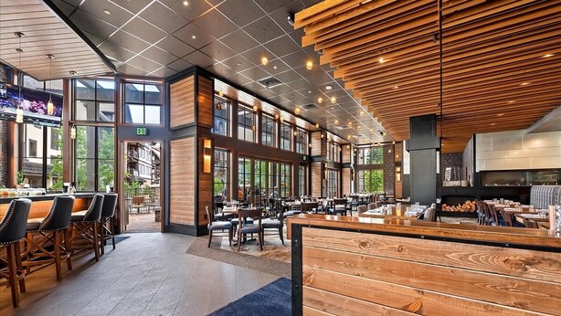 A spacious restaurant with high ceilings, wooden accents, and large windows.