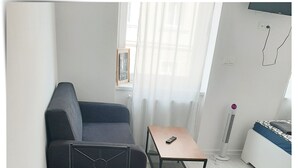 A modern living room with a dark sofa, a small wooden table, and a black metal table. - SouvenirAppart Sienkiewicza 3B (Bydgoszcz)