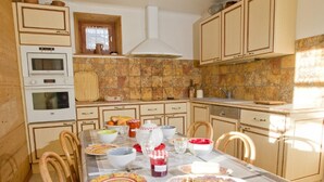 A kitchen with a dining table set for a meal, featuring a variety of dishes and utensils. - Spacious 3-room apartment with Wi-Fi and parking in Saint-Chaffrey (Saint-Chaffrey)