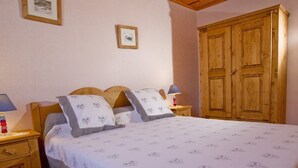 A bedroom with a wooden bed, two bedside tables with lamps, a wardrobe, and two framed pictures on the wall. - Spacious 3-room apartment with Wi-Fi and parking in Saint-Chaffrey (Saint-Chaffrey)