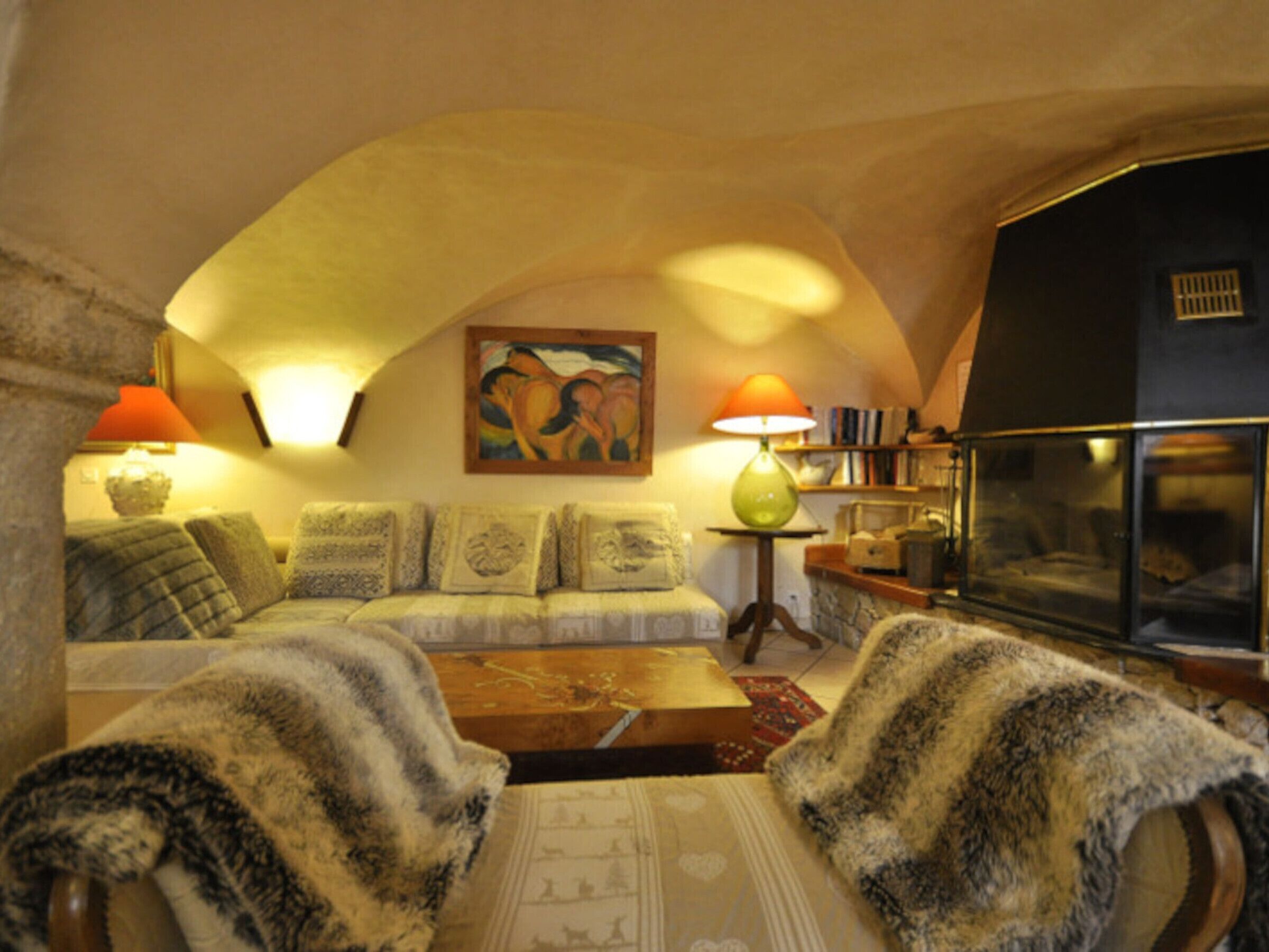 Una sala de estar acogedora con un sofá, sillones, una mesa de centro, un cuadro y una estantería.