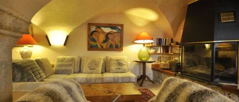 Una sala de estar acogedora con un sofá, sillones, una mesa de centro, un cuadro y una estantería.