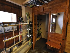 A wooden interior with a ski rack, a mirror, and a bench.