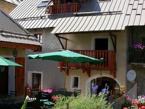 Un edificio con un balcone, un ombrellone verde e un giardino fiorito.