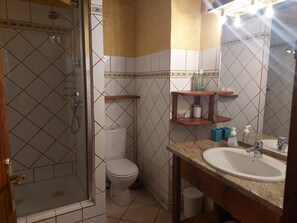 A bathroom with a shower, toilet, sink, and shelves with toiletries.