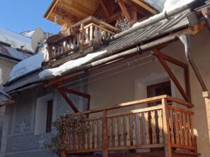 A wooden balcony with snow on the roof and railings.
