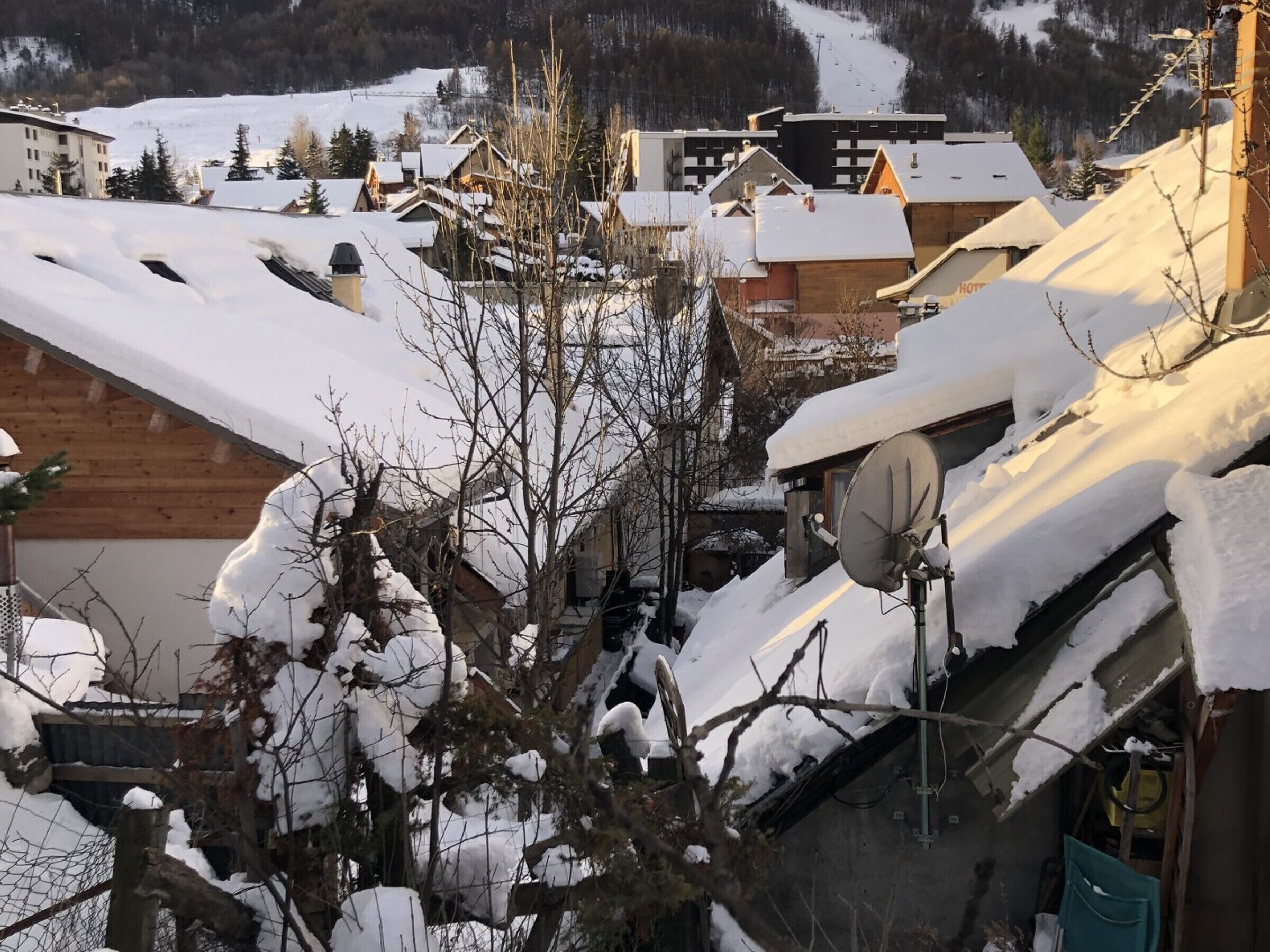 A snowy village with traditional wooden houses and a ski slope in the background.