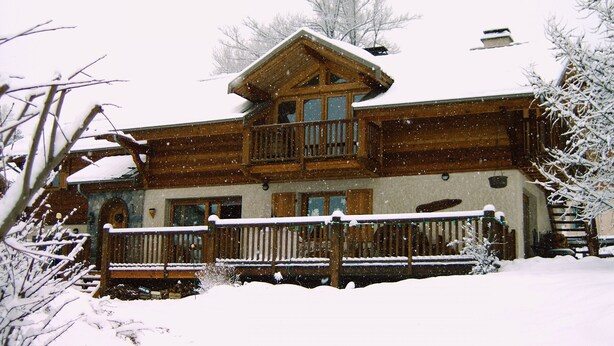 A wooden lodge with a balcony and a snow-covered roof.