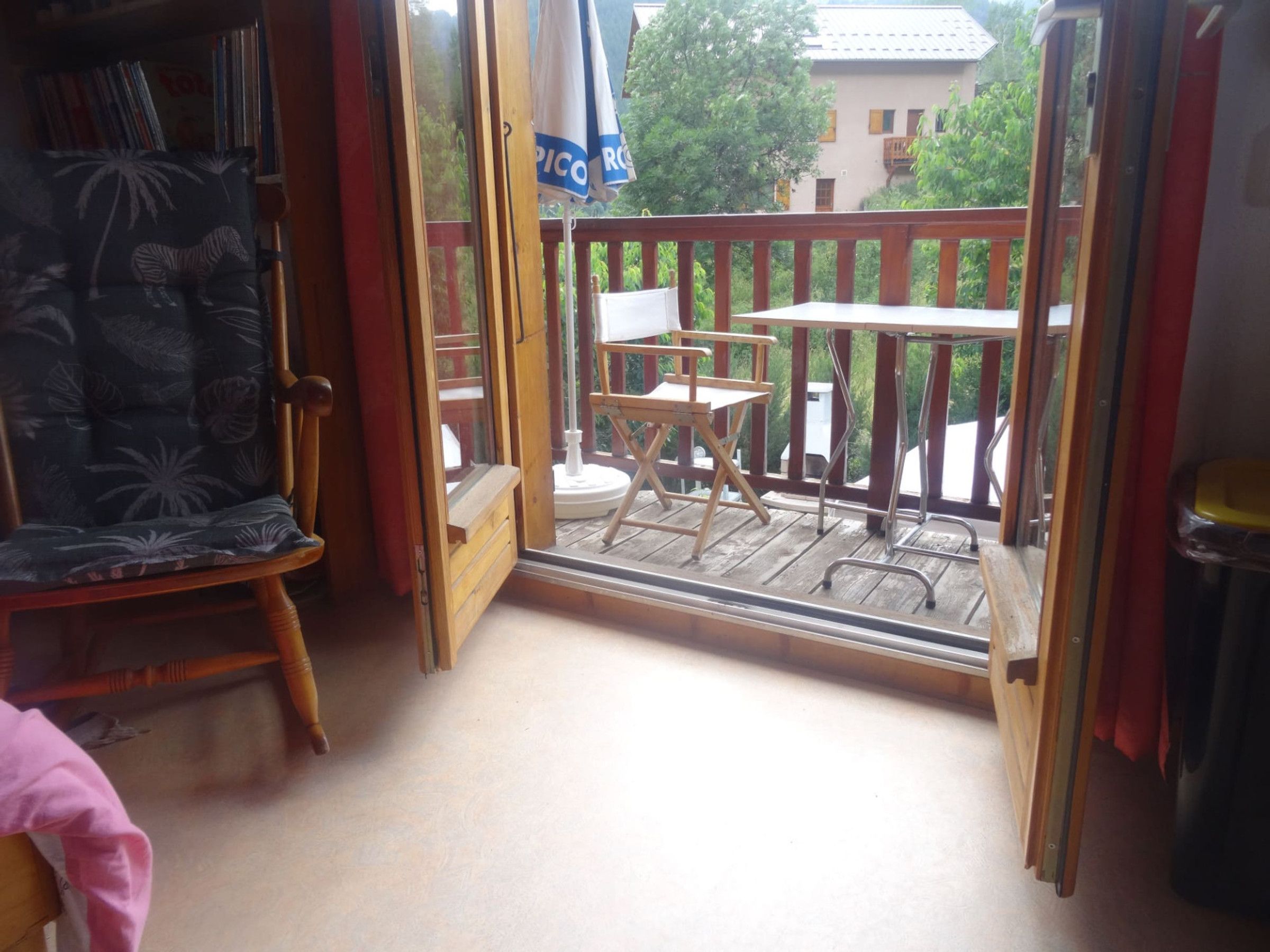 A balcony with a wooden railing, a chair, and a small table.