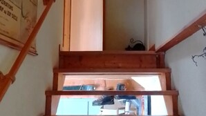 A wooden staircase with a metal railing, a door, and a wall with a poster.