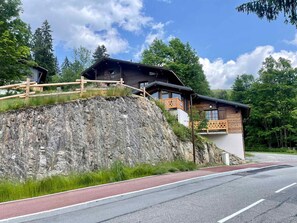 A mountain lodge with a wooden exterior, a stone retaining wall, and a red pathway.