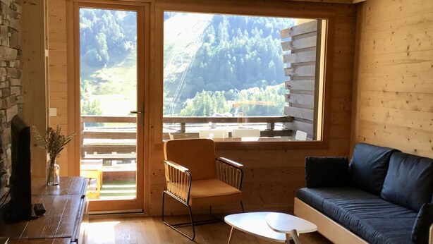 L'intérieur d'un chalet en bois, avec un canapé, un fauteuil et une petite table.