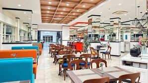A modern restaurant with wooden ceiling beams, bright lighting, and a mix of seating including tables and booths. - d'primahotel Jemursari Surabaya (Surabaya)