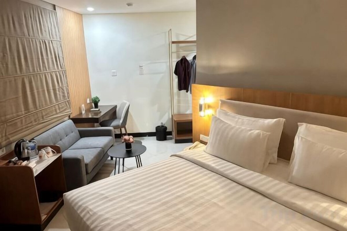 Une chambre d’hôtel avec un lit, un canapé, une petite table et un bureau.