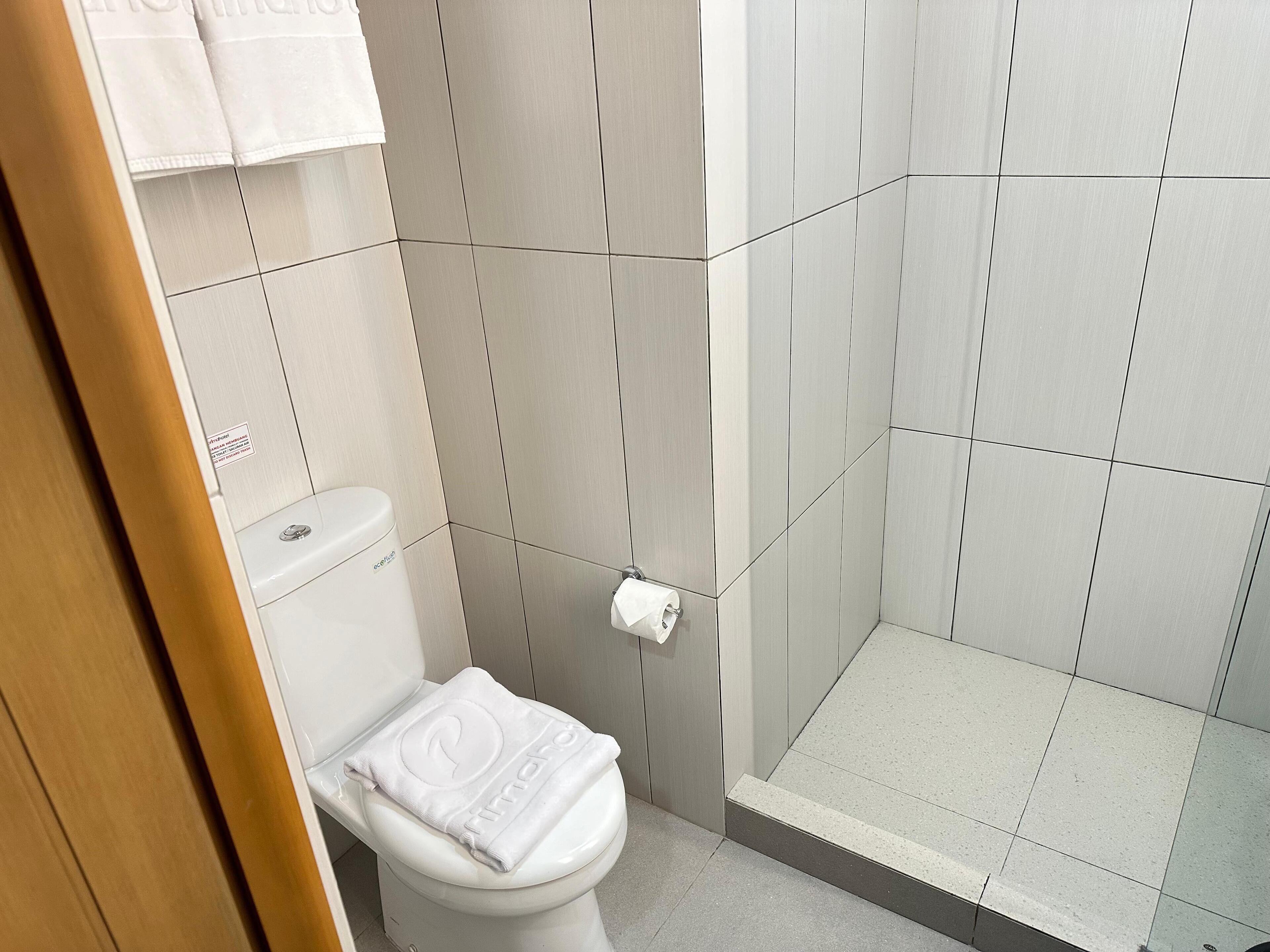 A bathroom with a toilet, a shower, and a towel rack.