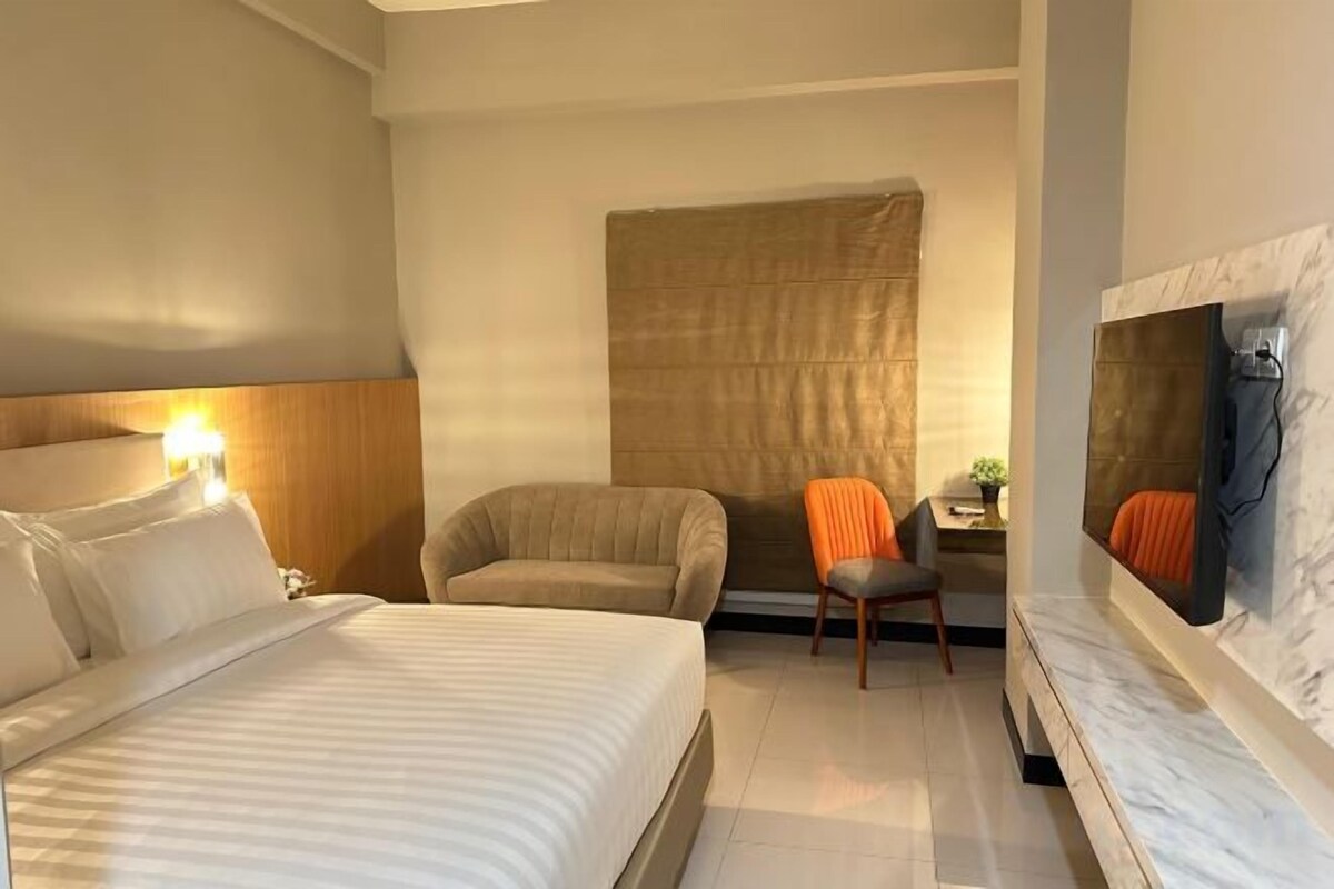 Een hotelkamer met een bed, een stoel, een bureau en een televisie.