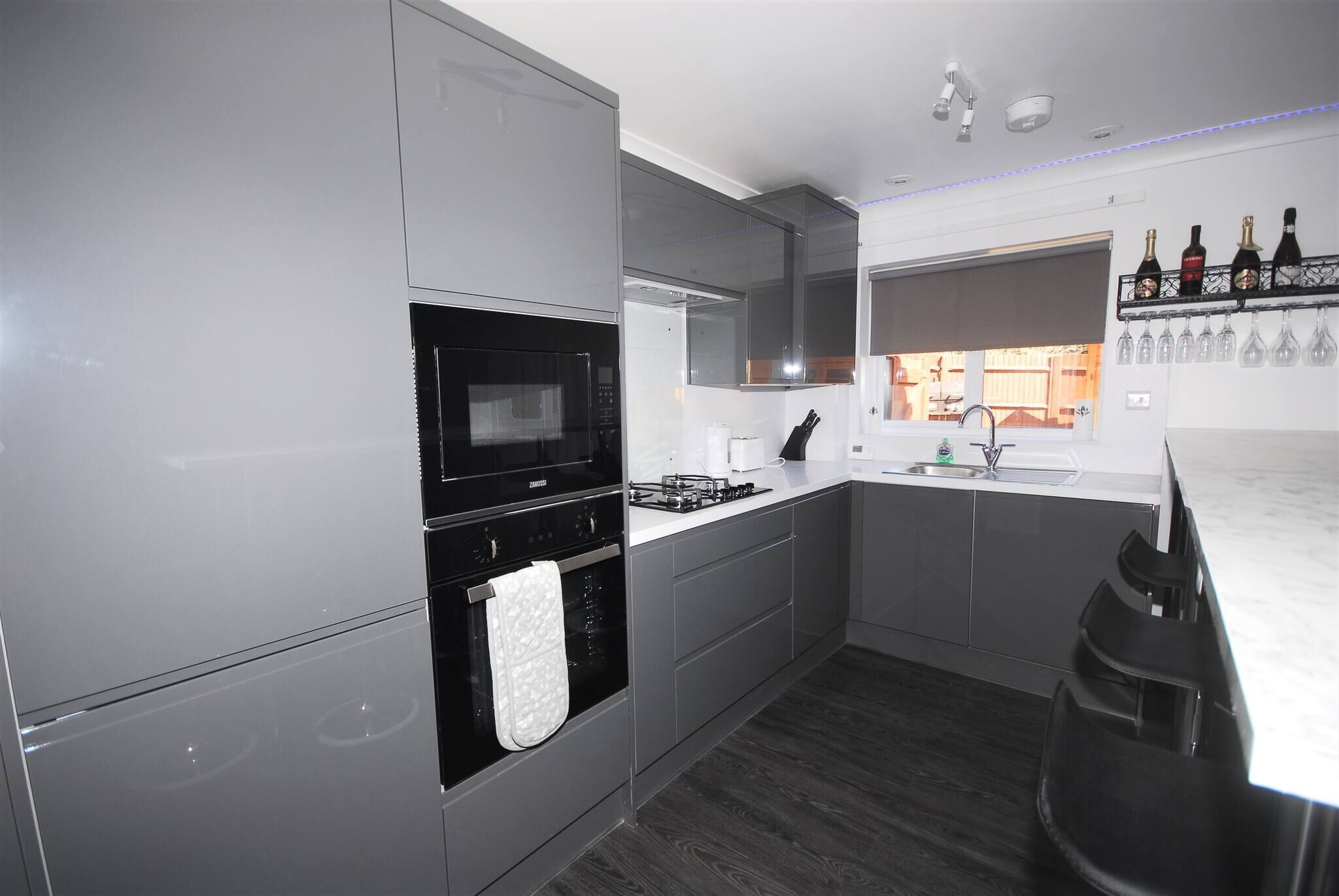 Une cuisine moderne avec des meubles de couleur grise, un micro-ondes noir, une cuisinière à gaz et un four encastré.